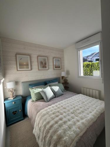 une chambre avec un grand lit et une fenêtre dans l'établissement Perle des Sables Blancs, appartement entier à 100m de la plage avec parking privé, à Concarneau