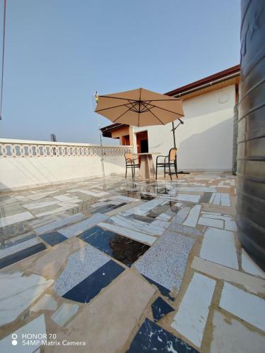 a patio with two chairs and an umbrella at Empress White House Accra in Tema