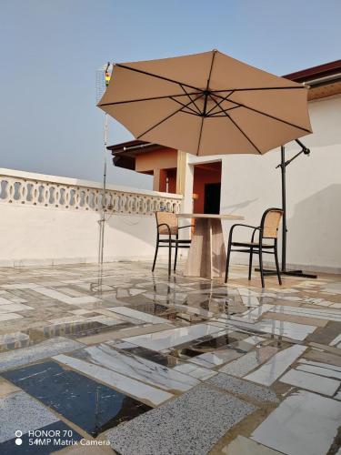 a patio with two chairs and a table with an umbrella at Empress White House Accra in Tema