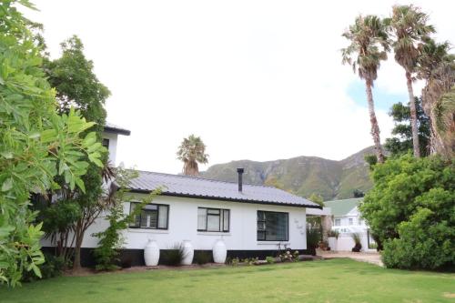 a white house with palm trees and mountains in the background at sonsandsee in Hermanus