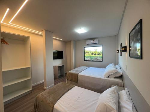 a hotel room with two beds and a tv at Bortolotti Residence in Penha