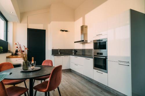 a kitchen with white cabinets and a table and chairs at La Casa de Moerkapel in Moerkapelle