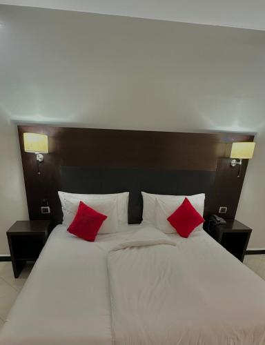 a large bed with two red pillows on it at Hotel Oscar 1 in Rabat