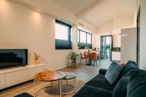 a living room with a couch and a tv and a table at La Casa de Moerkapel in Moerkapelle