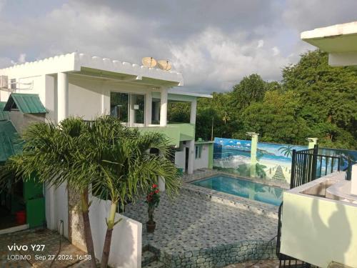 a house with a pool and a palm tree at Couple room in Holidays Beach Resort in Bolinao