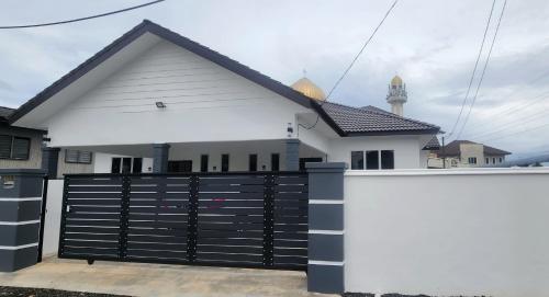 a white house with a black fence in front of it at MAB Homestay in Alor Setar