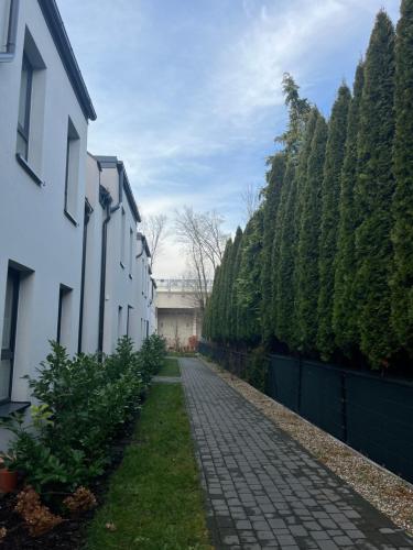 a cobblestone path between two white buildings and trees at Mieszkanie przy jeziorze w Ostródzie in Ostróda