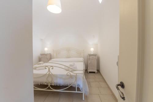 a white bedroom with a white bed and two night stands at Trulli di Mezza in Cisternino