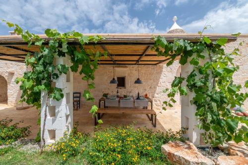 an outdoor patio with a table and a pergola at Trulli di Mezza in Cisternino