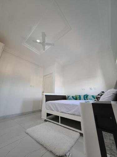 a white bedroom with a bed and a ceiling fan at Empress White House Accra in Tema