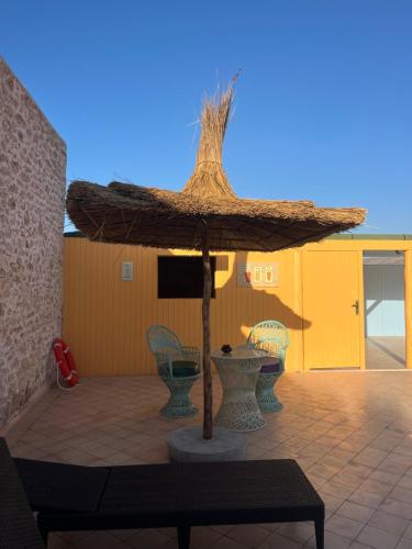 a large straw umbrella on a patio with chairs at The Mogador's Oasis in Akermoud