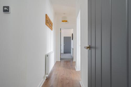 a hallway with white walls and a wooden floor at Spacious 3 bed flat- Free parking Edinburgh & Fife in Inverkeithing