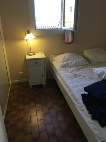 - une chambre avec un lit et une lampe sur une table de chevet dans l'établissement Maison entière avec deux chambres et un jardin Dans résidence avec piscine et parking privé Proche de la mer et de la marina Au calme, à Saint Cyprien Plage