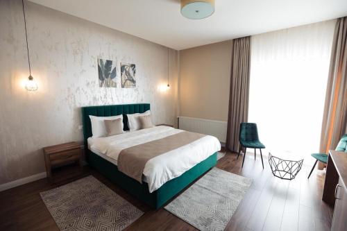 a bedroom with a large bed with a green headboard at Hotel Măgura Jina in Jina
