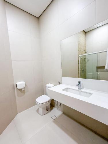 a white bathroom with a sink and a toilet at Vinhedo Plaza Hotel in Vinhedo