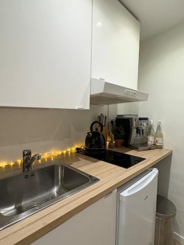 une cuisine avec des armoires blanches et un évier dans l'établissement Studio de Charme, Plein centre, à LʼIsle-sur-la-Sorgue