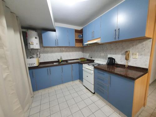a kitchen with blue cabinets and white appliances at Quinto Elemento City in Villa Carlos Paz