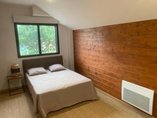 une chambre avec un lit et un mur en bois dans l'établissement L'Aiglon, à Ax-les-Thermes