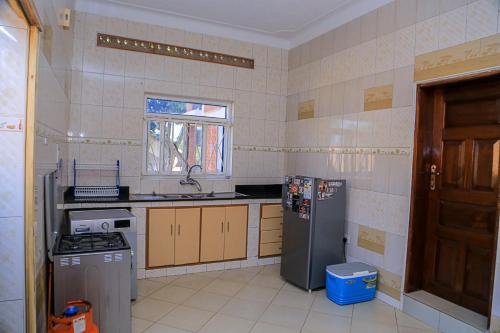 a small kitchen with a refrigerator and a sink at Garden Of Eden in Kampala