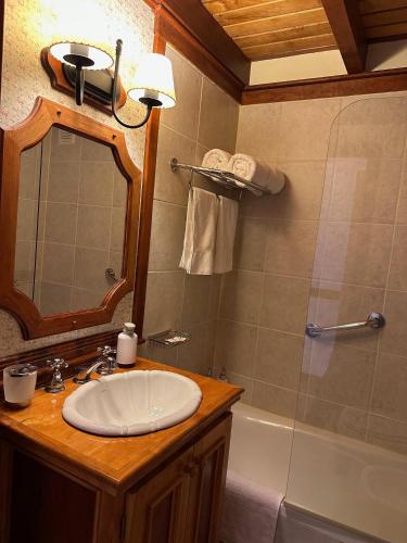 a bathroom with a sink and a mirror and a tub at Ushuaia Lodge in Ushuaia