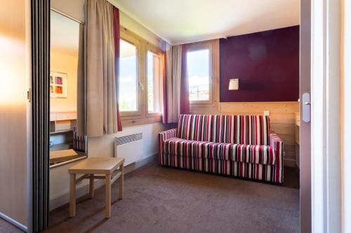 a living room with a striped couch and a table at Résidence Plagne Lauze - maeva Home - Studio 4 Personnes - Sélection MAE-4434 in Mâcot La Plagne