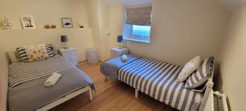 a bedroom with two beds and a window at Bee Cottage in Sandown