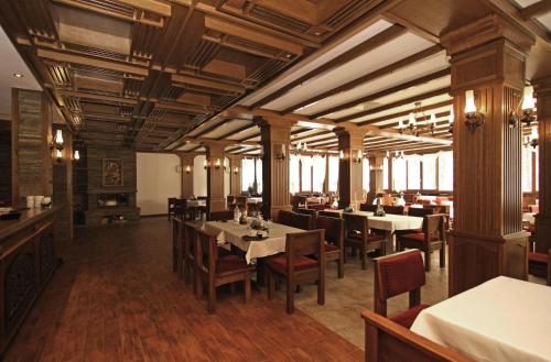 a restaurant with wooden ceilings and tables and chairs at Hotel Bozhentsi in Chernevtsi
