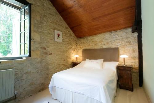 - une chambre avec un lit blanc dans un mur en pierre dans l'établissement Huge Dordogne House, heated pool, 5 acres, à Saint-André-dʼAllas