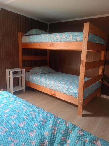 a bedroom with two bunk beds and a table at Cabaña Renacer a 10 min del aeropuerto in Puerto Montt