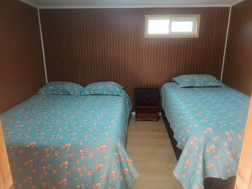 a bedroom with two beds and a window at Cabaña Renacer a 10 min del aeropuerto in Puerto Montt