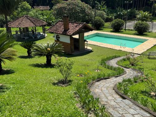 a garden with a swimming pool and a gazebo at Re-Canto dos Pássaros - Mendes in Mendes