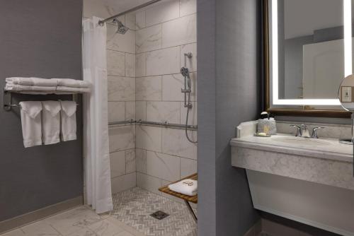 a bathroom with a shower and a sink and a mirror at Hotel Roanoke & Conference Center, Curio Collection by Hilton in Roanoke