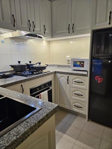 a kitchen with white cabinets and a black refrigerator at Entire Space T3 Centralidade do Kilamba, Luanda in Luanda