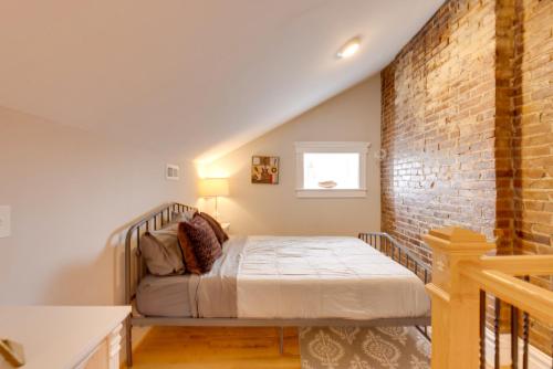 Un dormitorio con una cama y una pared de ladrillo. en Walkable Area Spacious Apt in Dtwn St Louis, en Soulard