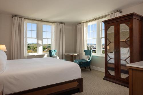 a bedroom with a bed and two chairs and windows at Hotel Roanoke & Conference Center, Curio Collection by Hilton in Roanoke