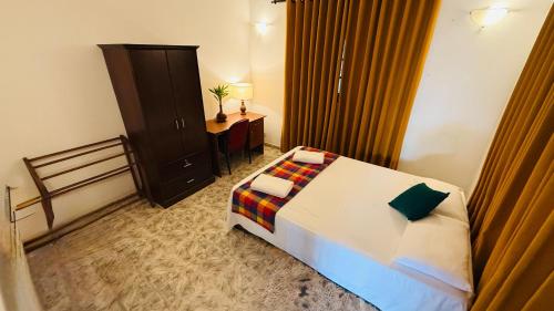 a bedroom with a bed and a cabinet and a table at Cinnamon Walauwaa in Piliyandala