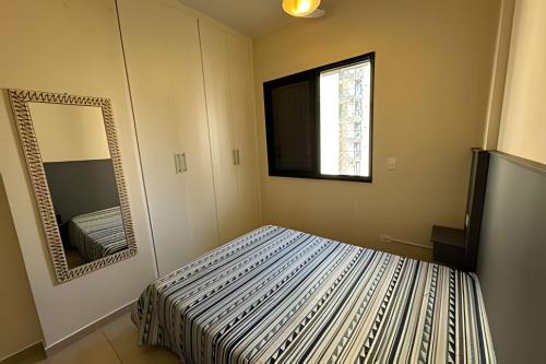a bedroom with a bed and a mirror at Paraíso com piscina: Pitangueiras Lazer Completo in Guarujá