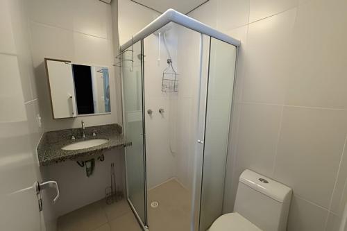 a bathroom with a shower and a toilet and a sink at Paraíso com piscina: Pitangueiras Lazer Completo in Guarujá