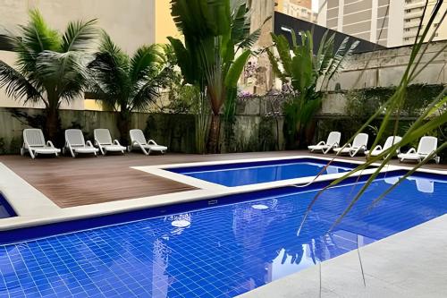 a swimming pool with chairs and a swimming pool at Paraíso com piscina: Pitangueiras Lazer Completo in Guarujá