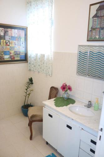 a bathroom with a sink and a vase of flowers on a counter at Sobrado da Casa Azul - Penedo in Itatiaia