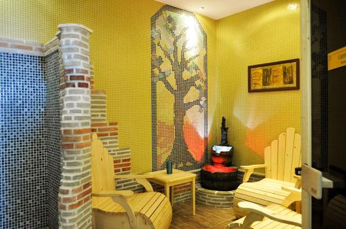 a room with a yellow wall with chairs and a table at Hotel Bozhentsi in Chernevtsi