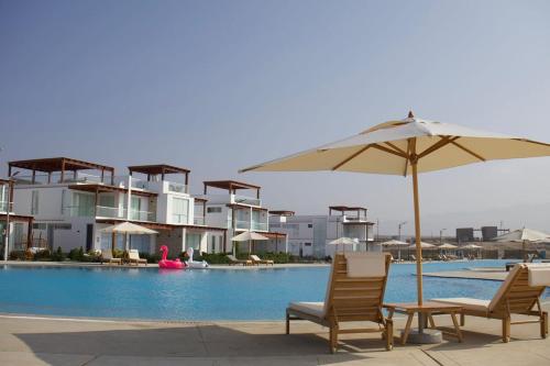 two chairs and an umbrella next to a swimming pool at Casa de Playa - Asia - SELENE beach house in Asia