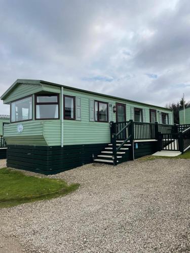 a green mobile home with a porch and stairs at Pet Friendly Caravan - Slaley Forest - Sleeps 4 in Hexham