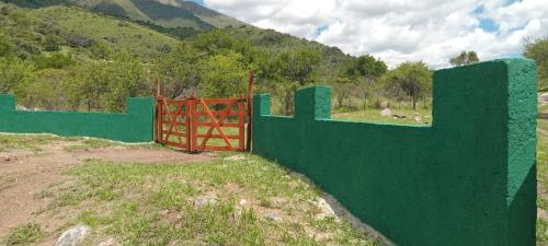 a green fence with a red gate in a field at Los Jilgueros in Los Hornillos