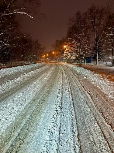 a snow covered street at night with street lights at Apartament Muszyna in Muszyna