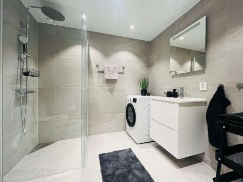a bathroom with a shower and a washing machine at Seaside seaview apartment in Tromsø