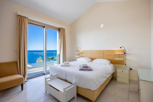 a bedroom with a large bed and a large window at Villa Stella Sunset in Nea Dimmata