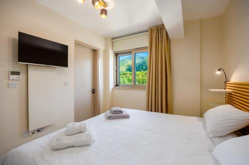 a bedroom with a large white bed and a window at Villa Stella Sunset in Nea Dimmata