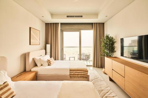 a hotel room with two beds and a television at Luxury 59th Floor Apartment with Stunning Seaview & Access to Infinity Pool on 64th Floor Burj Views in Dubai