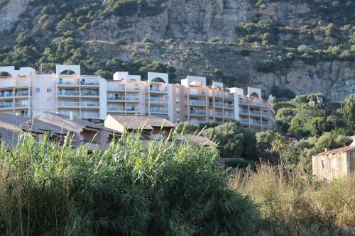 un grand immeuble blanc sur une montagne dans l'établissement Beau studio Routes des Sanguinaires proche de la plage, à Ajaccio